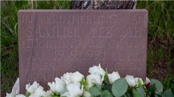 Teilnehmer der Gedenkkundgebung für den 1991 bei einem Brandanschlag getöteten ghanaischen Asylbewerber Samuel Yeboah haben an einem Gedenkstein Blumen abgelegt.