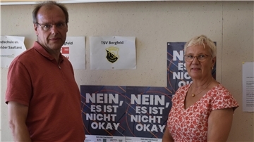Thomas Kaessler, Geschäftsführer des Landessportbundes Bremen (LSB), und LSB-Präsidentin Eva Quante-Brandt zeigen das Plakat zur Prävention Sexualisierter Gewalt, das in Sporthallen in Bremerhaven und Bremen hängen wird.