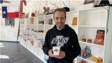 Ein Mann steht in einem Laden und hält eine Packung Eis in der Hand.