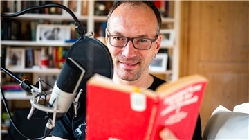 Toby Baier, "Einschlafen"-Podcaster, sitzt in seinem Arbeitszimmer und spricht einen neuen Beitrag ein.