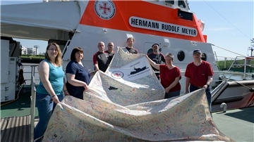 Tolle Aktion der Ehrenamtlichen: Zusammen mit den Bremerhavener Seenotrettern zeigen sie eins von vier signierten Segeln.