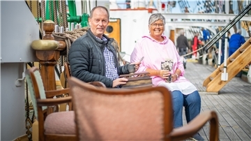 Eine Frau und ein Mann sitzen auf dem Deck des "Schulschiff Deutschland".