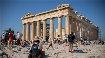 Touristen an einem heißen Tag bei ihrem Besuch des Parthenon-Tempels auf dem Akropolis-Hügel in Athen.