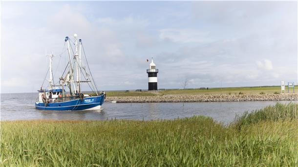 Krabbenkutter fährt am Leuchtturm Kleiner Preuße in Wremen vorbei.