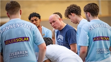 Ein Basketball-Trainer spricht in einer Auszeit mit seinen Spielern. Es ist Tomasz Kumaszynski mit der U19-Mannschaft der Eisbären.