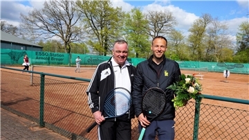 Zwei Männer stehen vor einem Tennisplatz.