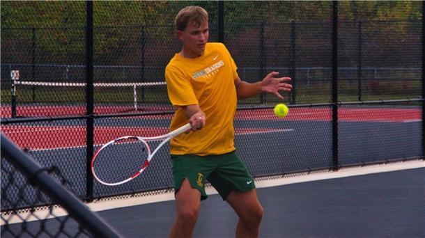 Ein Mann im orangefarbenen T-Shirt spielt Tennis.