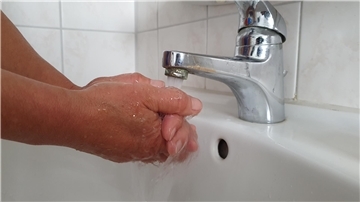Hände werden unter laufendem Wasser aus einem Wasserhahn gewaschen
