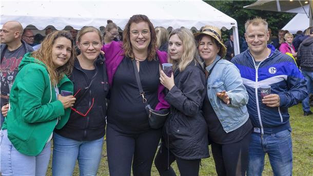 Die Gäste der Village Move Party stehen in einer Reihe und trinken. 