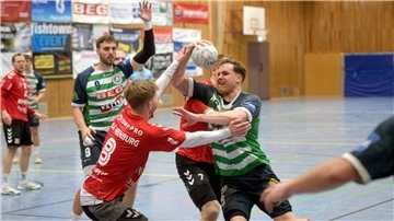 Handballer kämpfen auf dem Feld um den Ball.