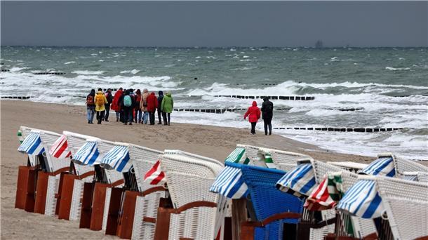 Trotz Wind und Wetter: Eine Wandergruppe ist an der aufgewühlten Nordsee bei Graal-Müritz unterwegs. Im Norden Deutschlands lässt der Sommer noch auf sich warten.
