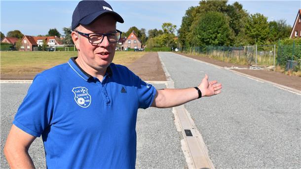 Mann in einem blauen Polohemd und eine Kappe auf einem Sportplatz
