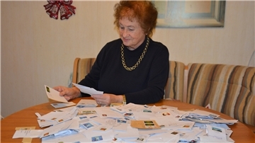 Eine Frau sortiert Briefmarken auf einem Tisch.