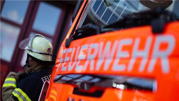 Eine Einsatzkraft der Feuerwehr steht neben einem Einsatzfahrzeug
