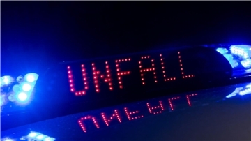 Das Blaulicht auf einem Fahrzeug der Polizei leuchtet in der Dunkelheit, während auf dem Display der Hinweis «Unfall» zu lesen ist. (zu dpa: «Auto rammt Sattelzug - 28-Jähriger stirbt»)
