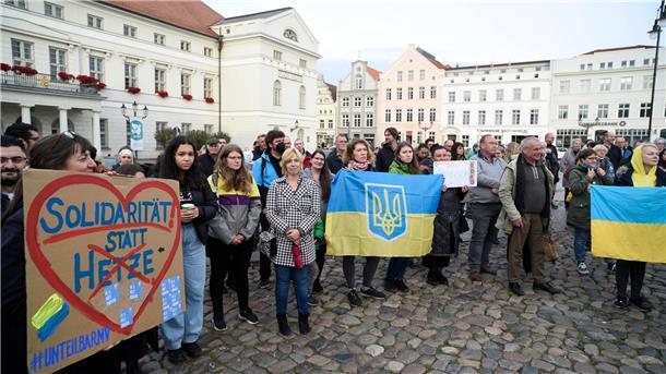 Ukrainische Frauen und weitere Teilnehmer stehen bei einer Mahnwache auf dem Wismarer Marktplatz.