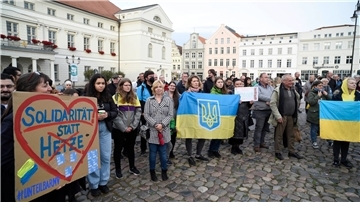 Ukrainische Frauen und weitere Teilnehmer stehen bei einer Mahnwache auf dem Wismarer Marktplatz.