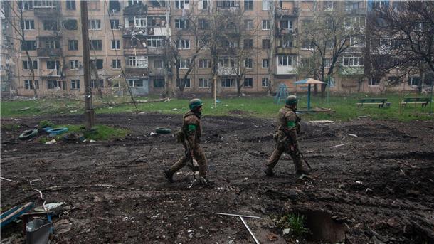 Ukrainische Soldaten gehen in Bachmut an stark beschädigten Gebäuden vorbei.