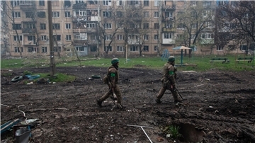 Ukrainische Soldaten gehen in Bachmut an stark beschädigten Gebäuden vorbei.