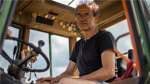 Ulf Allhoff-Cramer, Landwirt, sitzt in seinem Traktor. Der Bio-Bauer macht den Autokonzern VW mitverantwortlich für Schäden an seinem Hof. Er will zusammen mit Greenpeace vor Gericht erreichen, dass VW 2030 keine Verbrennungsfahrzeuge mehr verkauft.