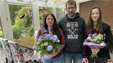 Zwei Frauen mit Blumen und ein Mann. Ulf Thormählen ist der neue Inhaber des Allee-Cafés in Burhave, seine Frau Bianca und seine Tochter Gina werden es gemeinsam betreiben.