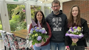 Zwei Frauen mit Blumen und ein Mann. Ulf Thormählen ist der neue Inhaber des Allee-Cafés in Burhave, seine Frau Bianca und seine Tochter Gina werden es gemeinsam betreiben.