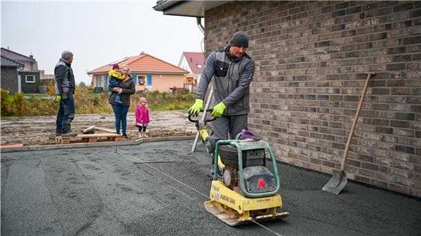Bauarbeiter richtet eine Fläche mit einem Arbeitsgerät.