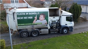 Ein Müllwagen steht vor einem Haus.