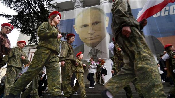 Uniformierte Jugendliche marschieren in Jalta anlässlich einer Aktion zum neunten Jahrestag der Krim-Annexion an einem Bild des russischen Präsidenten Wladimir Putin vorbei.
