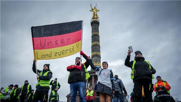 Bauernprotest ohne schnelle Diesel-Lösung „Unser Land zuerst!“ - Teilnehmer der Großkundgebung protestieren mit einer Deutschlandfahne vor der Siegerssäule.