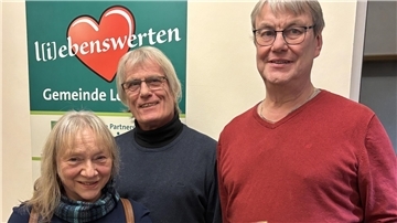 Drei Menschen lächeln in die Kamera. 