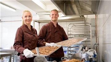 Eine Frau und ein Mann halten Backbleche in der Hand.
