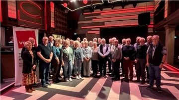 Mehrere Menschen stehen in einem Saal nebeneinander und posieren für ein Foto. 