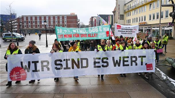 Menschen stehen auf der Straße und halten Banner hoch.