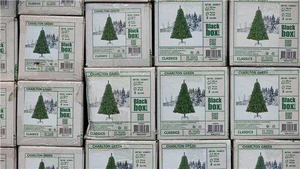 Welcher ist der beste Baum für die Umwelt? Verpackte Weihnachtsbäume aus Kunststoff (PVC) in einem Baumarkt.
