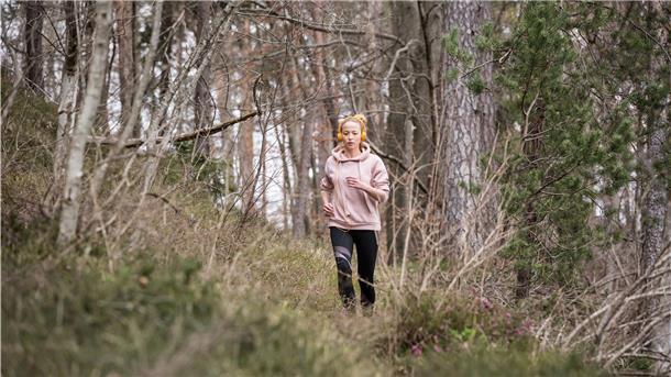 Eine Frau joggt durch den Wald.