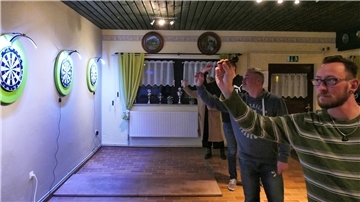 Vier Dartspieler des Schützenverein Mulsum zielen im Clubraum auf ihre Dartscheiben.