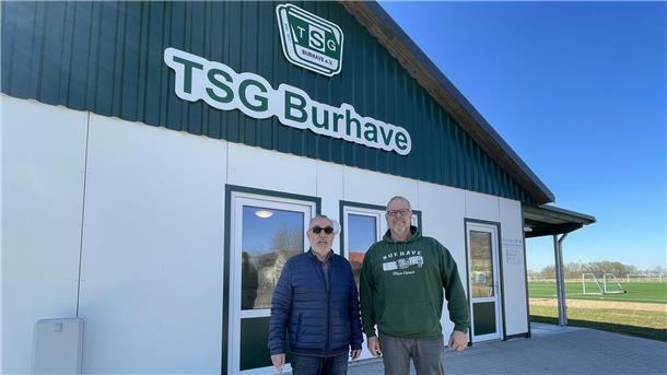Zwei Männer stehen vor einem Gebäude mit der Aufschrift TSG Burhave. Günter Thielemann und Volker Bliefernich sind voller Stolz auf den Neubau.