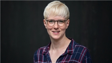 Eine blonde Frau mit Brille lächelt in die Kamera
