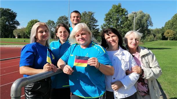 Eine Gruppe Menschen steht auf einem Sportplatz versammelt.