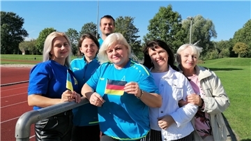 Eine Gruppe Menschen steht auf einem Sportplatz versammelt.