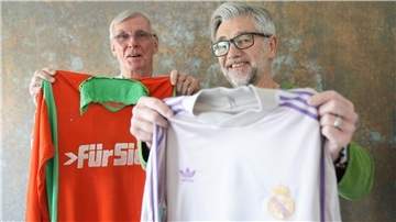 Zwei Männer halten Trikots von SFL Bremerhaven und Real Madrid.