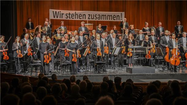 Vor dem 3. Sinfoniekonzert am Montag und Dienstag demonstrierten die Orchestermitglieder mit einem Banner ihre Geschlossenheit im Konflikt. Dafür gab es viel Beifall vom Publikum.