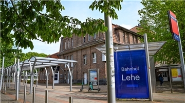 Vorplatz mit Bahnhofsgebäude und Schild „Bahnhof Lehe“.