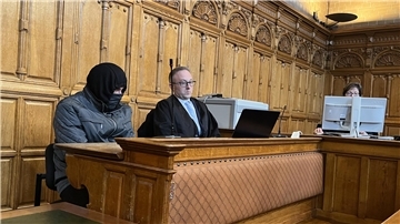 Mann mit Maske sitzt auf der Anklagebank. 