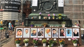 Vor dem Wahrzeichen der Stadt Hanau, dem Brüder Grimm-Denkmal auf dem Marktplatz, erinnern Bilder an Opfer des rassistisch motivierten Anschlags vom 19. Februar.