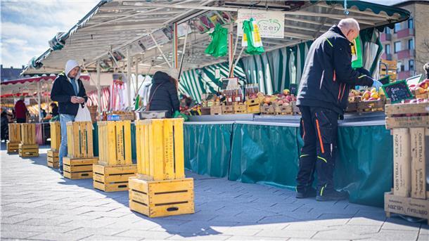 Vor den Marktständen weisen Schilder und Bodenmarkierungen auf die Abstandsregel zur Rücksichtnahme hin. Sie bieten auch Schutz im Osteransturm.