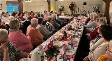 Vor vollem Saal stimmt Mia Ohlsen die Selsinger Landfrauen mit Stimme und Gitarre sowie auf Plattdeutsch und Dänisch aufs Fest ein.