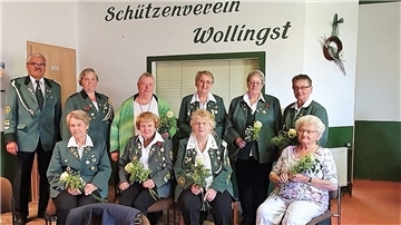 Die geehrten Schützinnen  sitzen zusammen und posieren für das Foto. Am Rand steht der Vereinsvorsitzende.