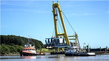 Ein Schwimmkran auf der Hunte hat ein Brückenbauteil am Haken